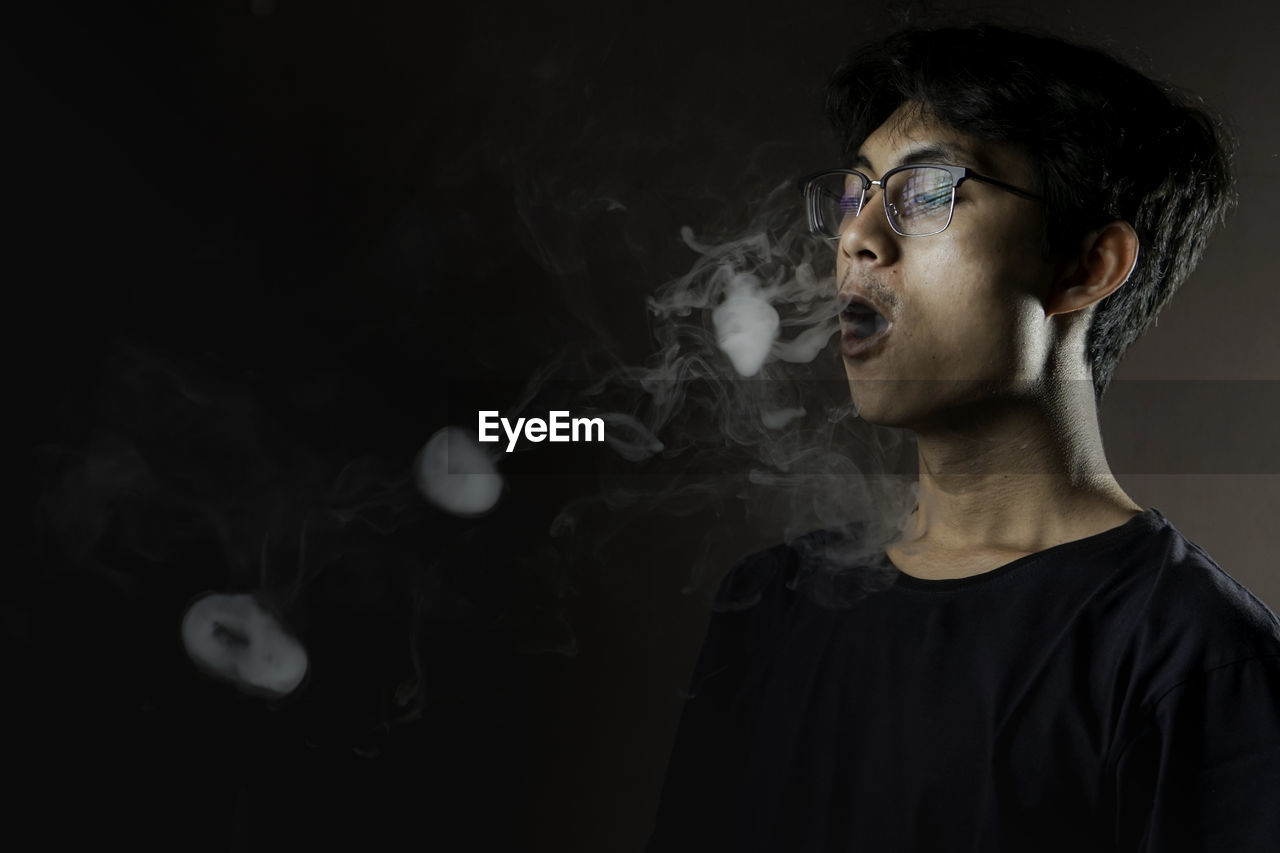 smoke, one person, darkness, black, smoking issues, adult, smoking, indoors, portrait, studio shot, headshot, black background, cigarette, glasses, eyeglasses, young adult, dark, bad habit, social issues, men, activity, sign, copy space, looking, warning sign