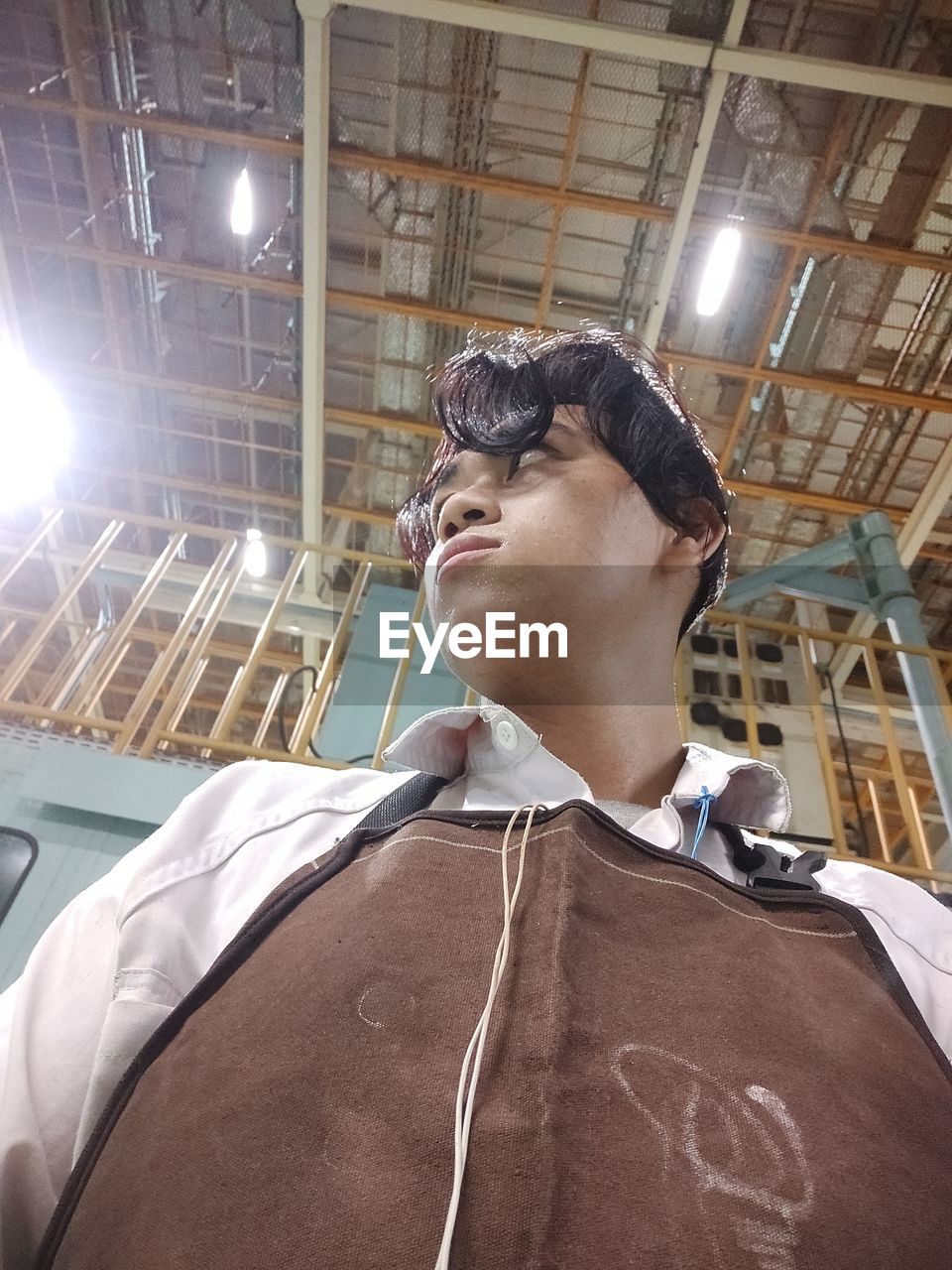 LOW ANGLE VIEW OF MAN LOOKING AT ILLUMINATED CEILING