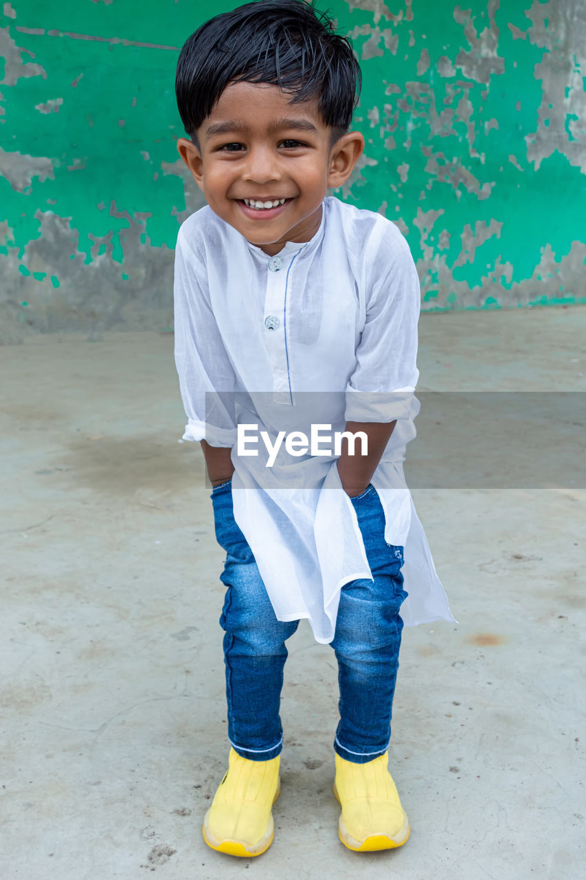 PORTRAIT OF A SMILING BOY STANDING ON BEACH