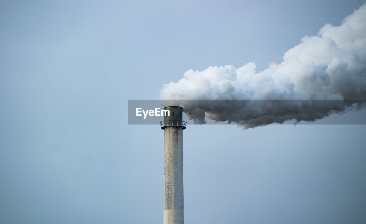 Smoke emitting from chimney against sky