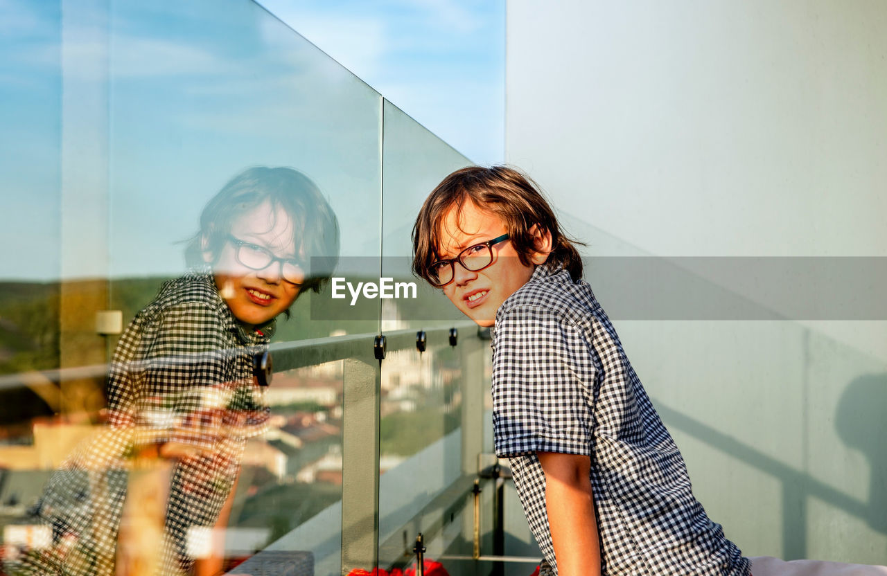 Rear view of a boy and his  reflection in glass