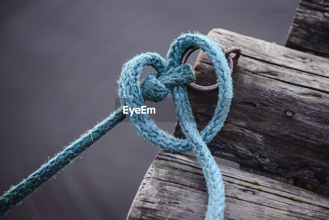 Close-up of rope tied to ring bollard on wood