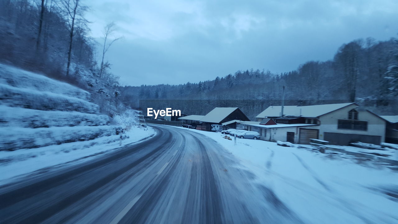 Road amidst snow covered trees against sky