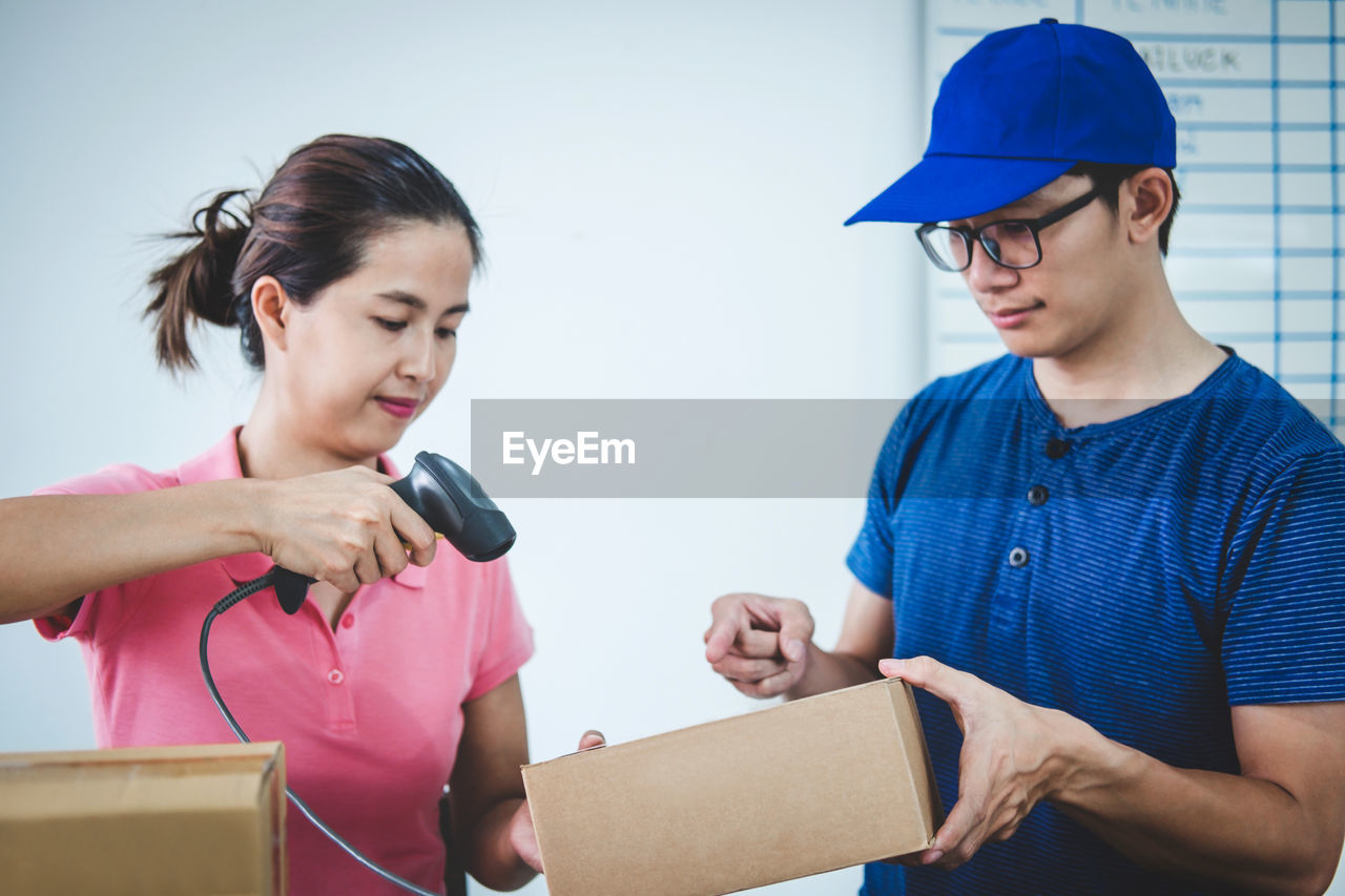 Businesswoman scanning while colleague holding box