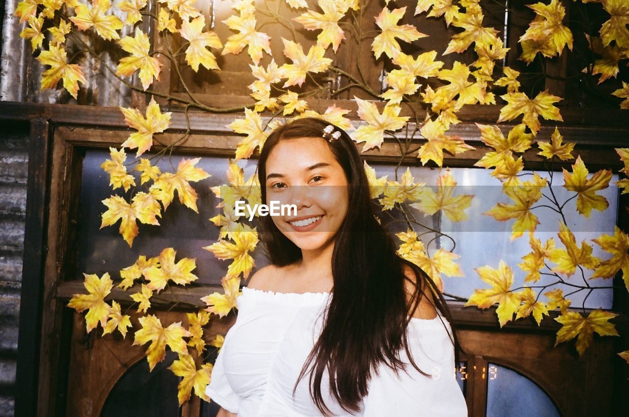 Portrait of woman standing against yellow leaves