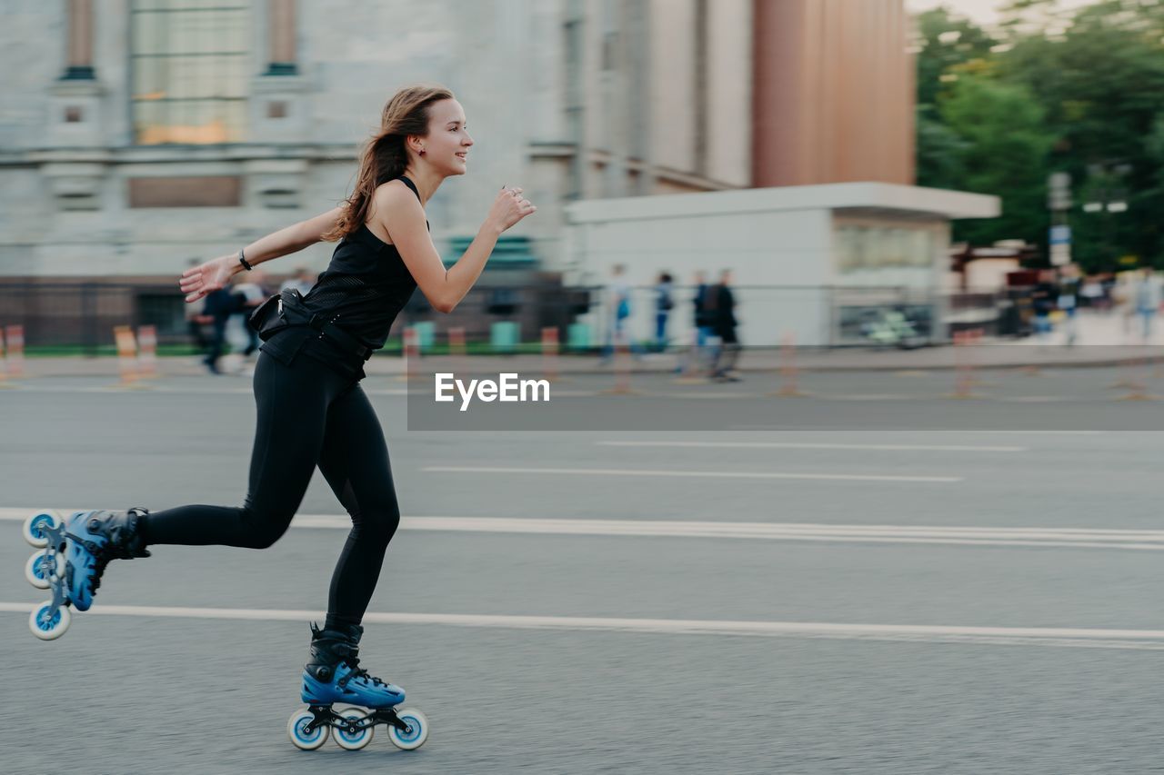 Full length of woman skateboarding on road in city