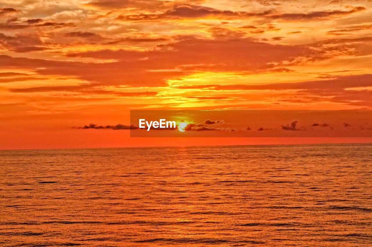 Scenic view of sea against dramatic sky during sunset