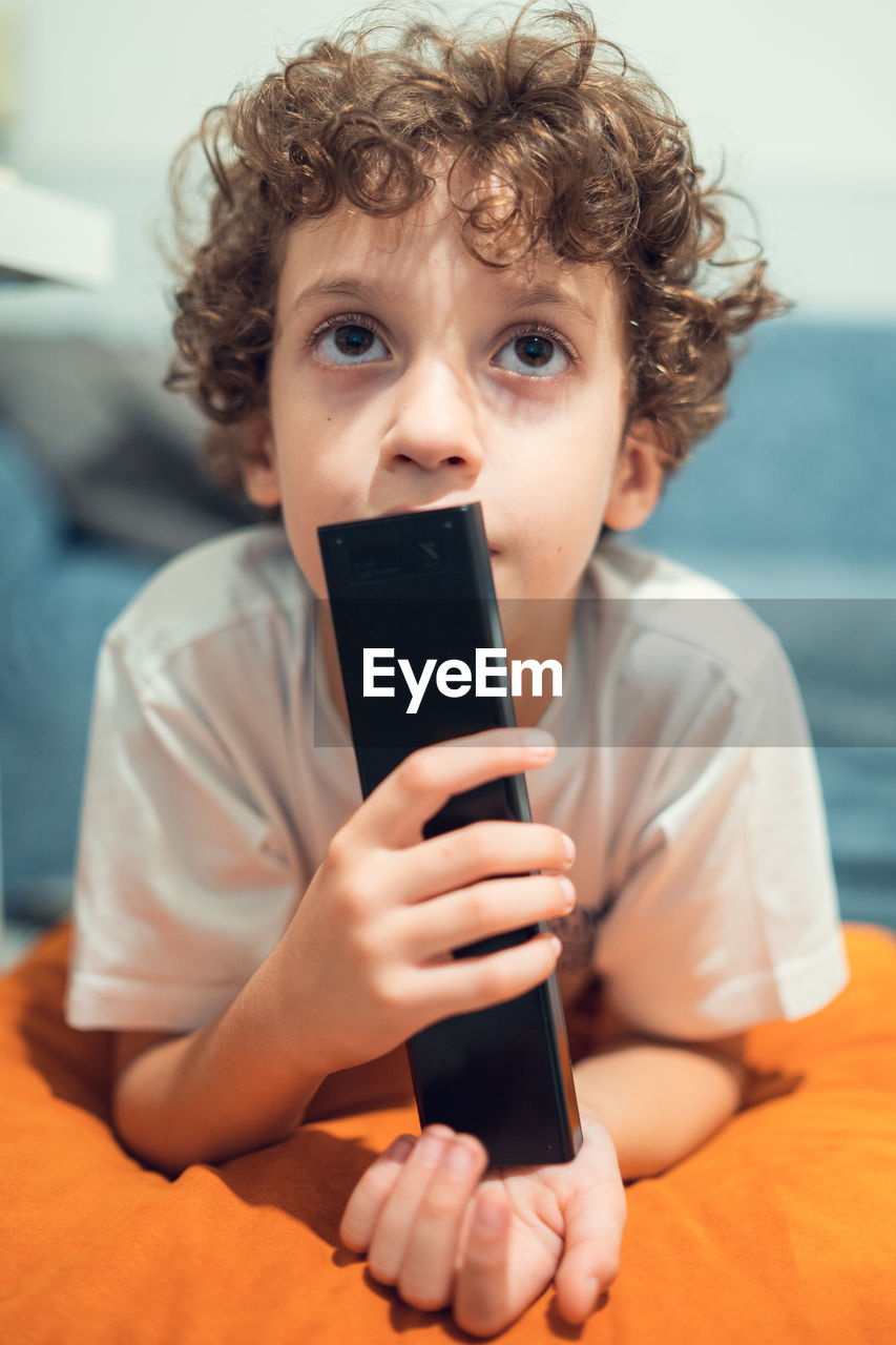 Boy watching tv holding the remote controller