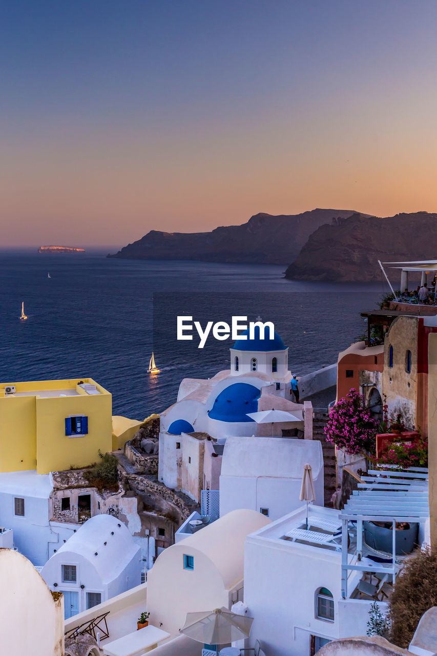 High angle view of buildings by sea against sky during sunset