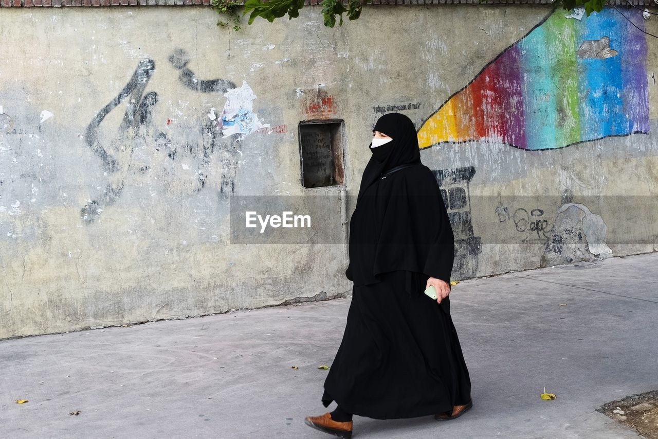 FULL LENGTH REAR VIEW OF WOMAN STANDING ON STREET