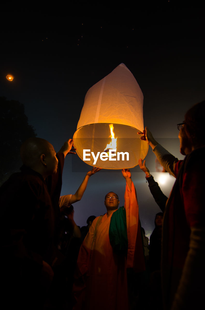 PEOPLE IN ILLUMINATED LANTERN AT NIGHT