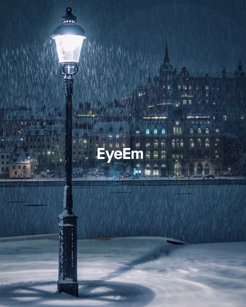 Snowfall over stockholm with old street lamp in foreground