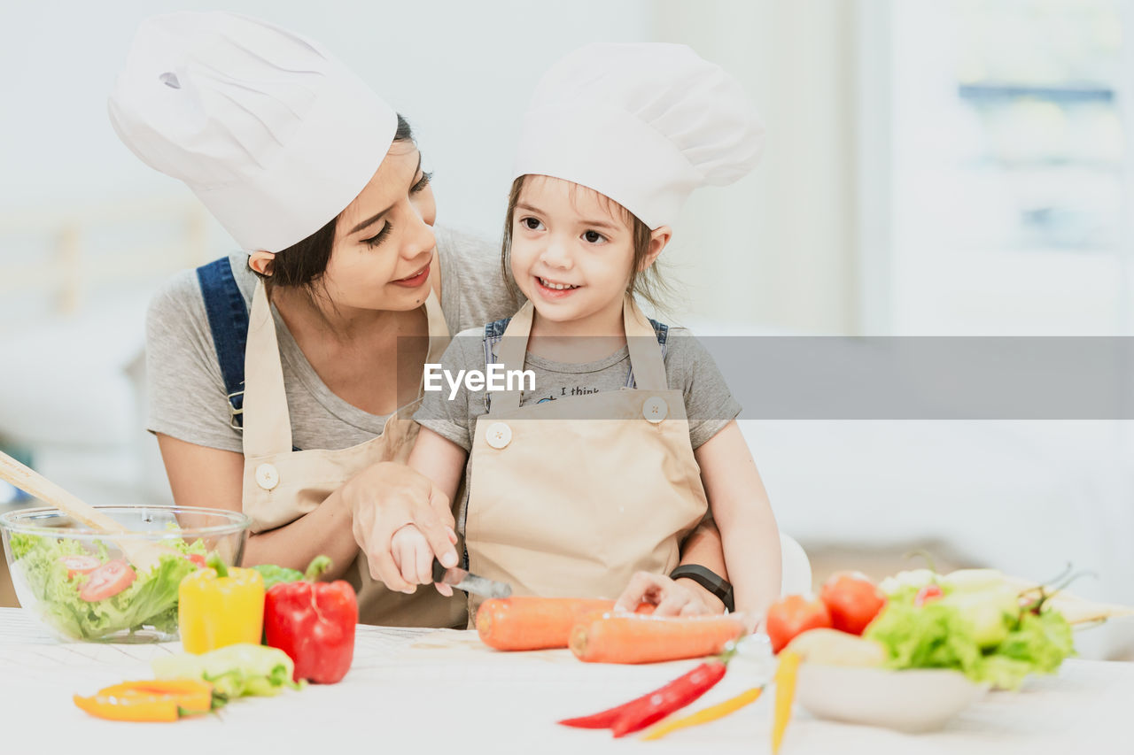 Mother and daughter preparing food on table