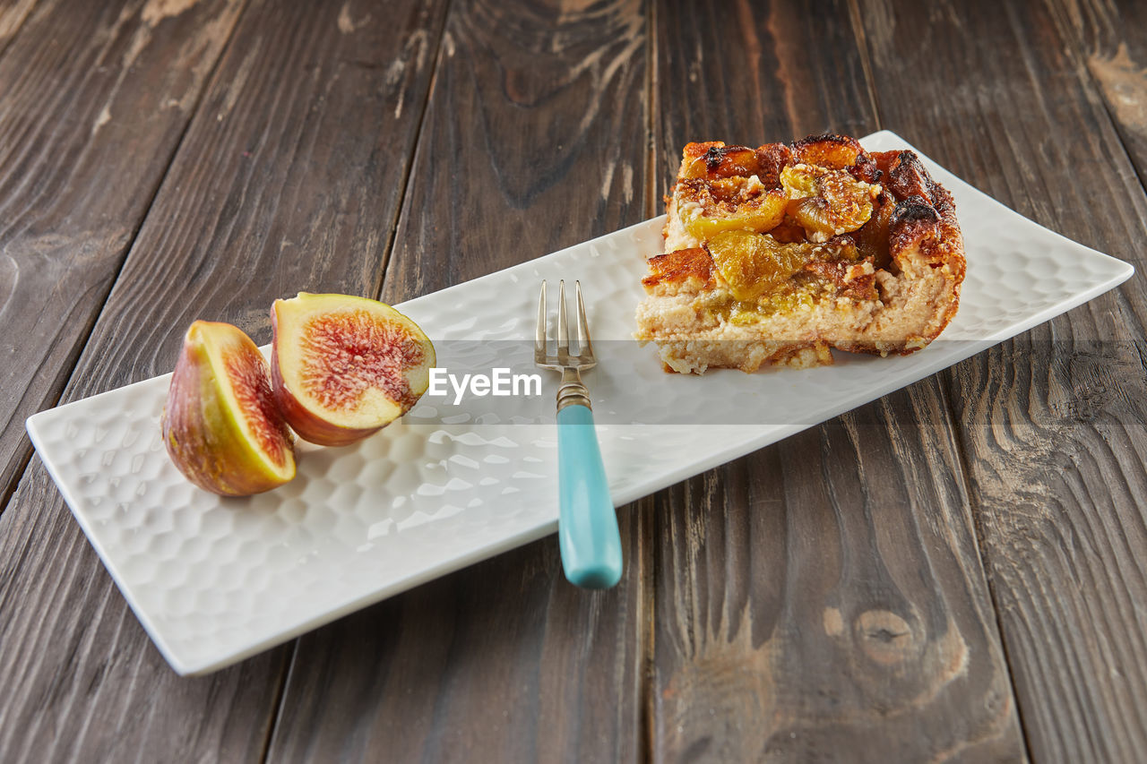 Clafoutis with figs and honey on white plate, on wooden background. french gourmet food