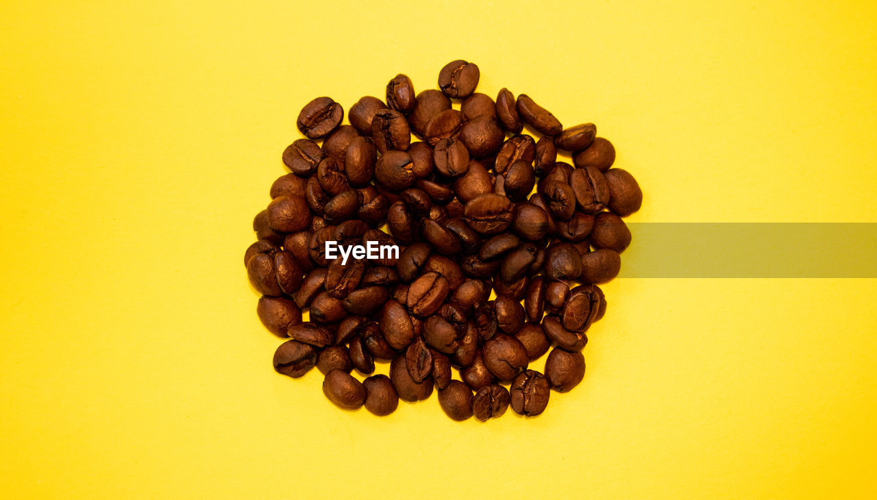 HIGH ANGLE VIEW OF COFFEE BEANS IN YELLOW BACKGROUND