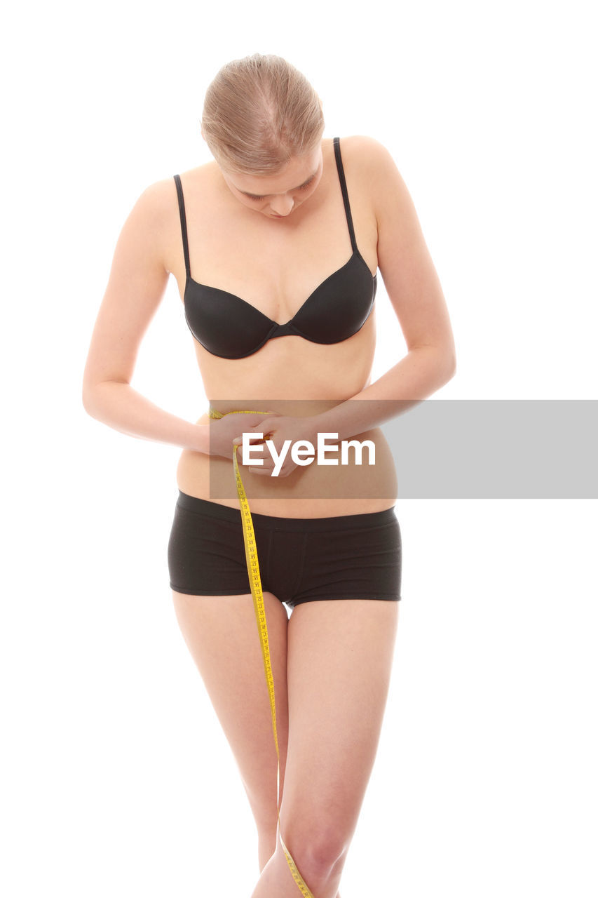 Woman holding tape measure against white background