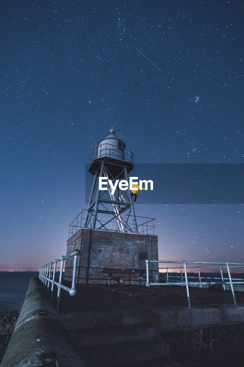 Man standing on lookout tower against sky at night