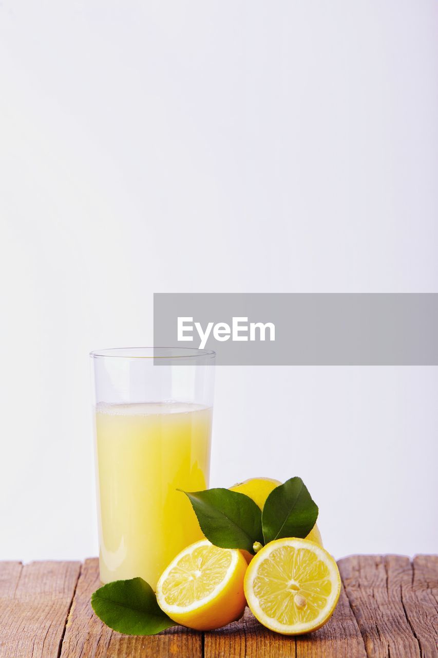 Glass with lemon and lemon juice on a white background