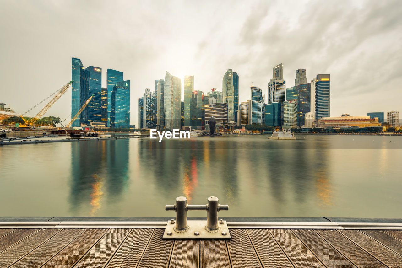 Modern buildings by bay against sky in city