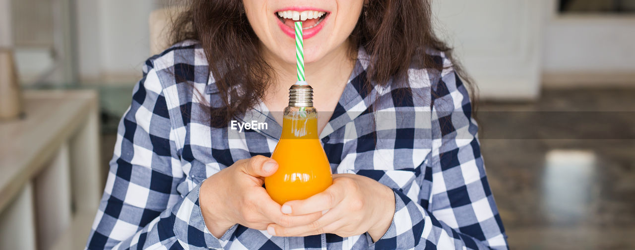 Woman with juice in electric bulb at home