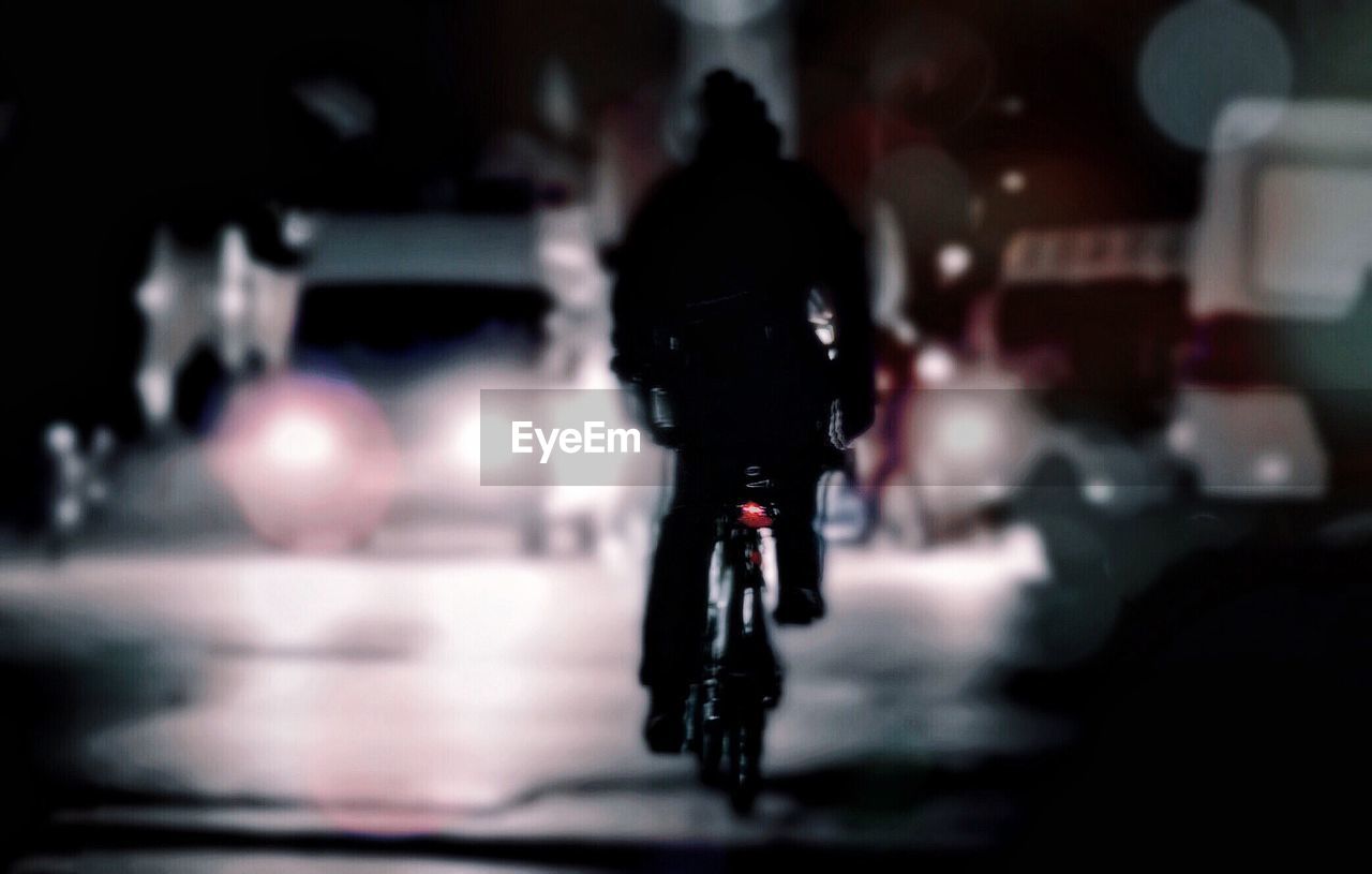 Silhouette man riding bicycle on road at night
