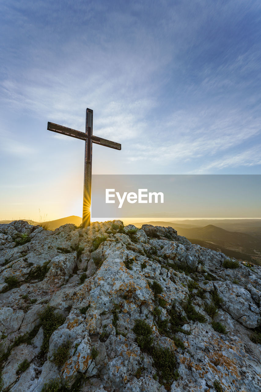 Christian symbol, wooden catholic cross on the top of a mountain at sunrise.
