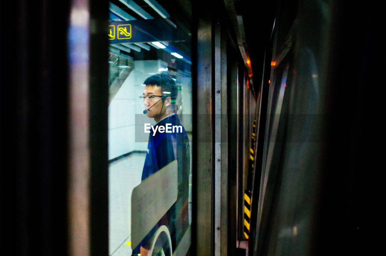 MAN LOOKING THROUGH TRAIN WINDOW