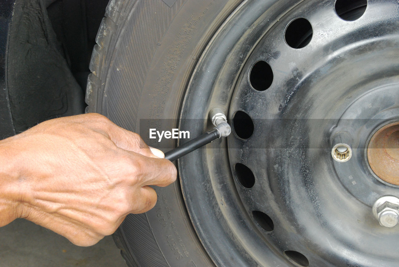 Cropped image of hand checking car tire with gauge