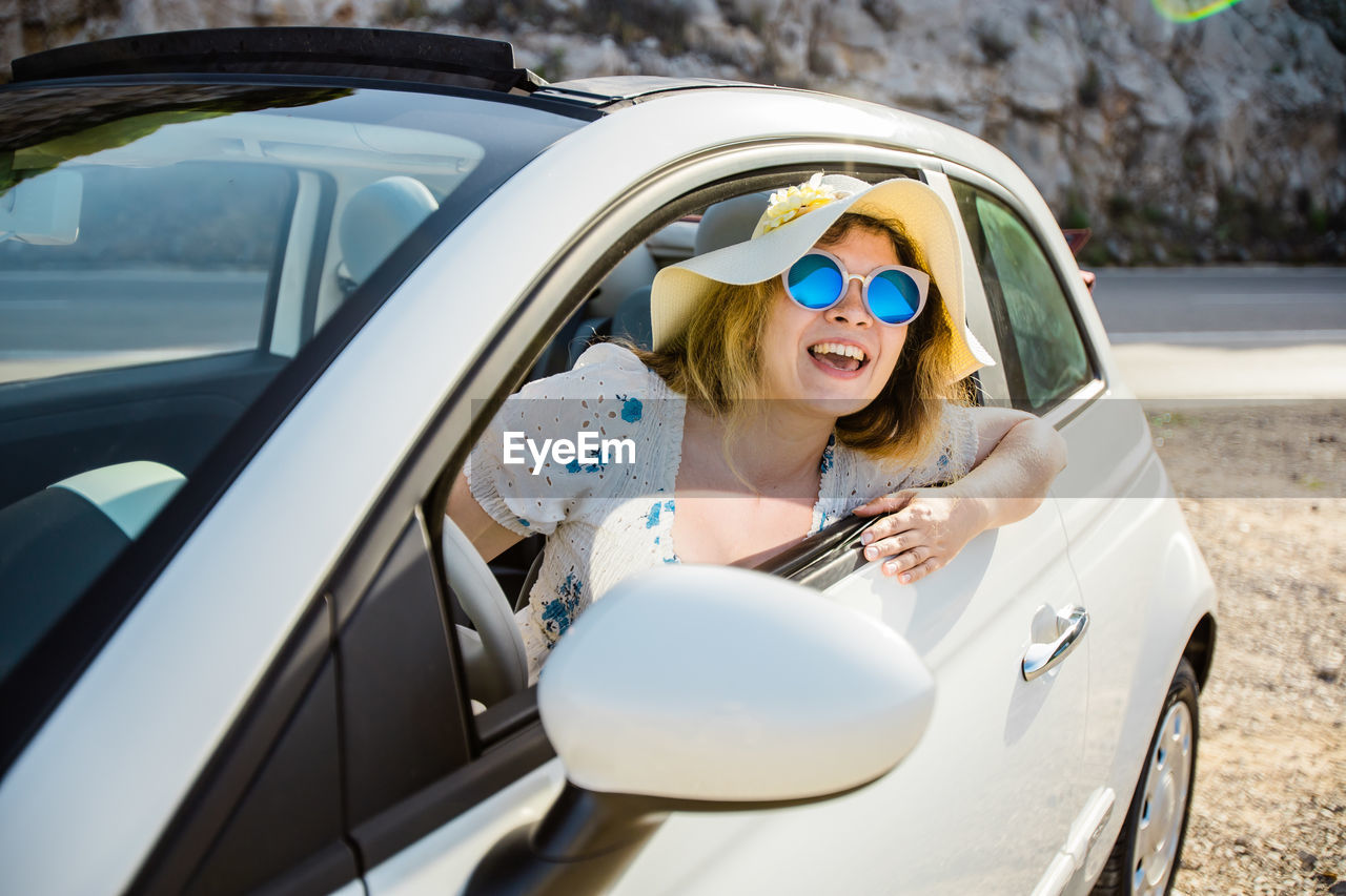portrait of young woman in car on road