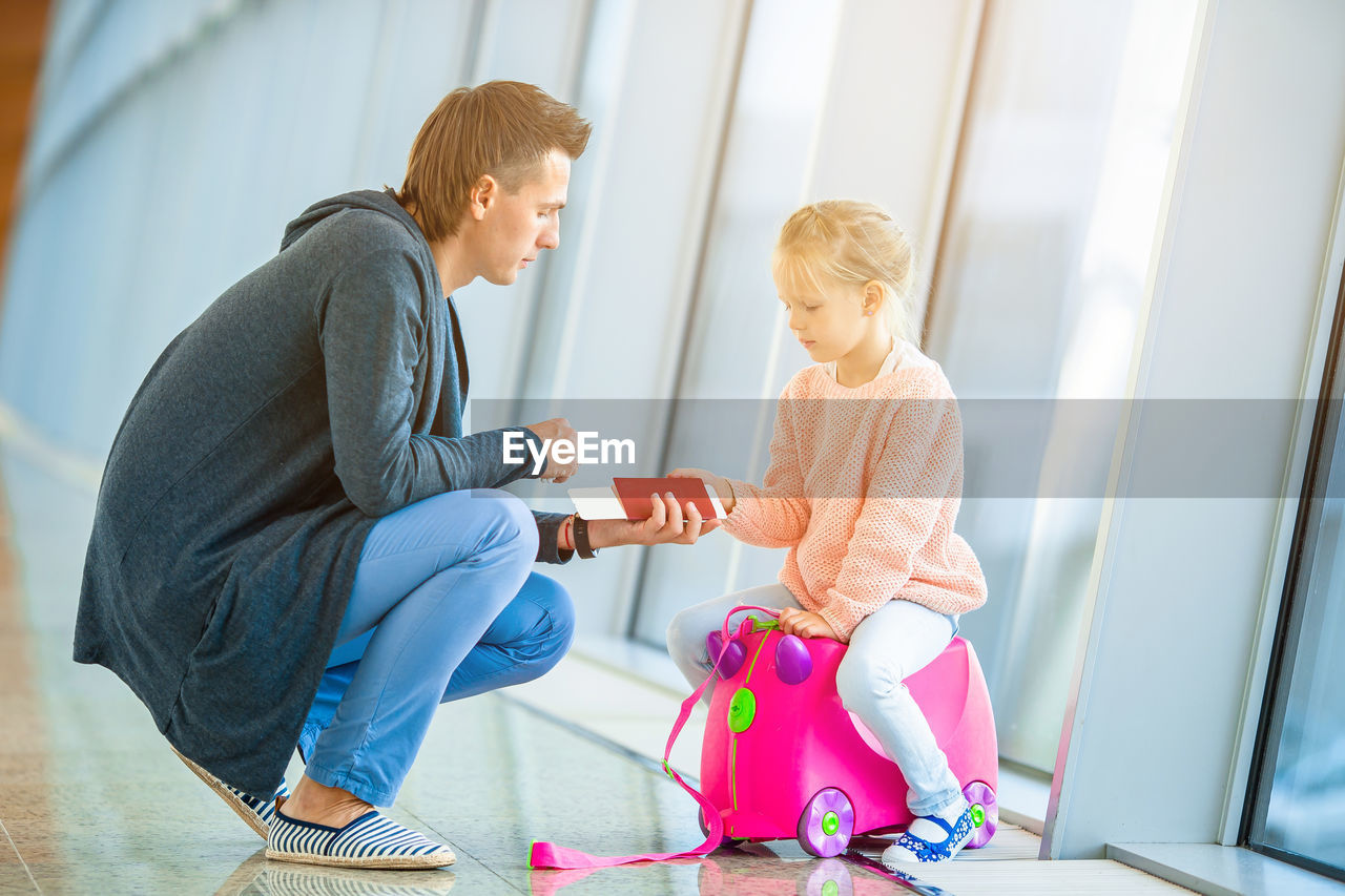 Full length of father holding passport at airport