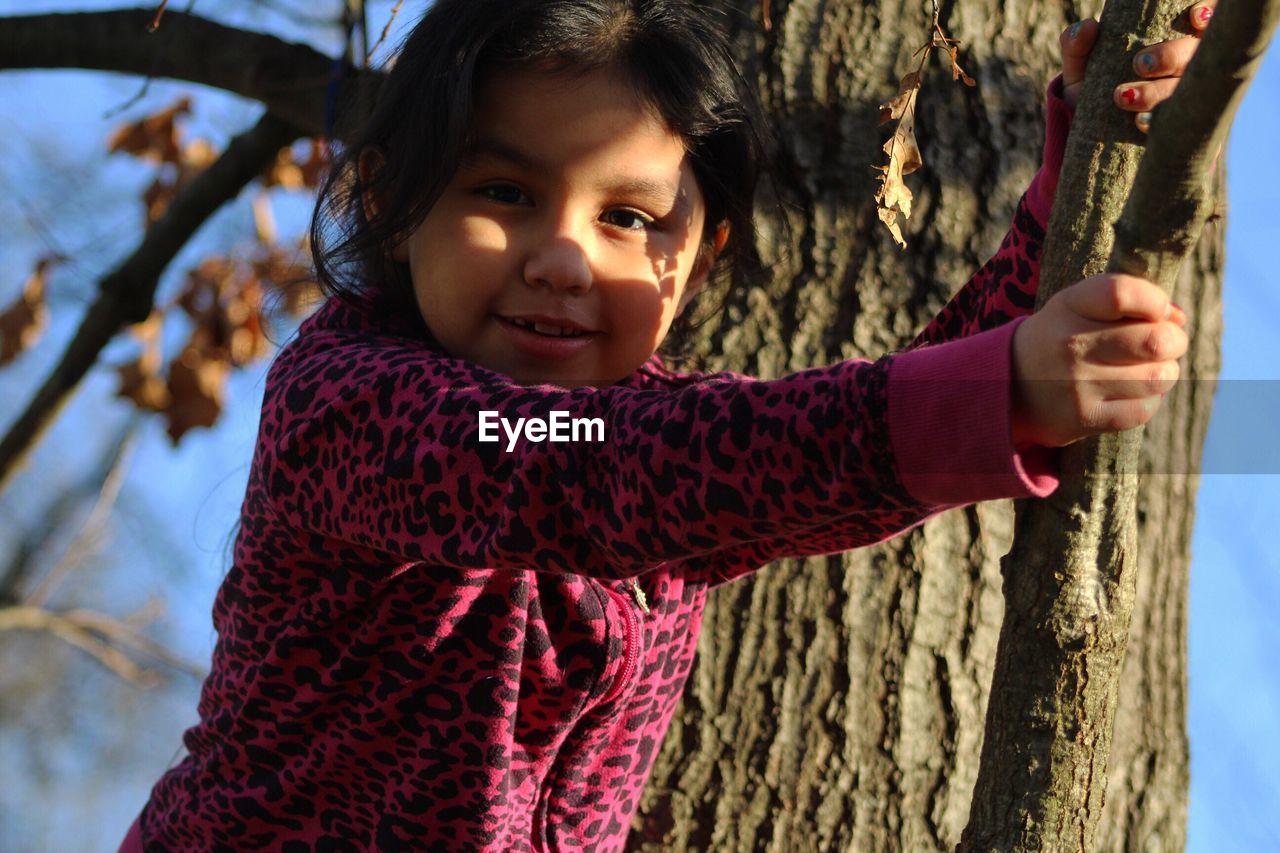 Portrait of girls standing on tree branch