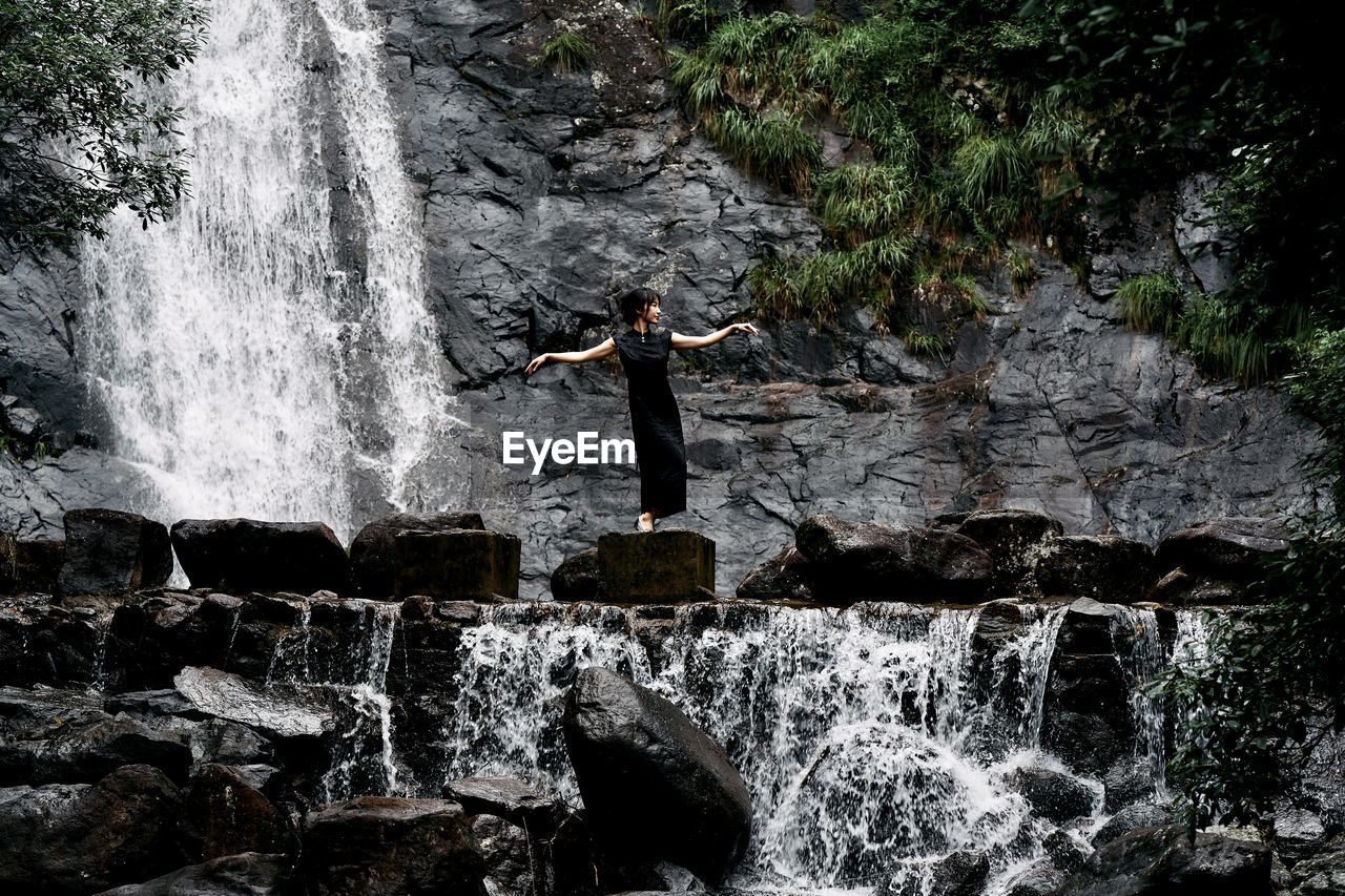 Rear view of man standing against waterfall