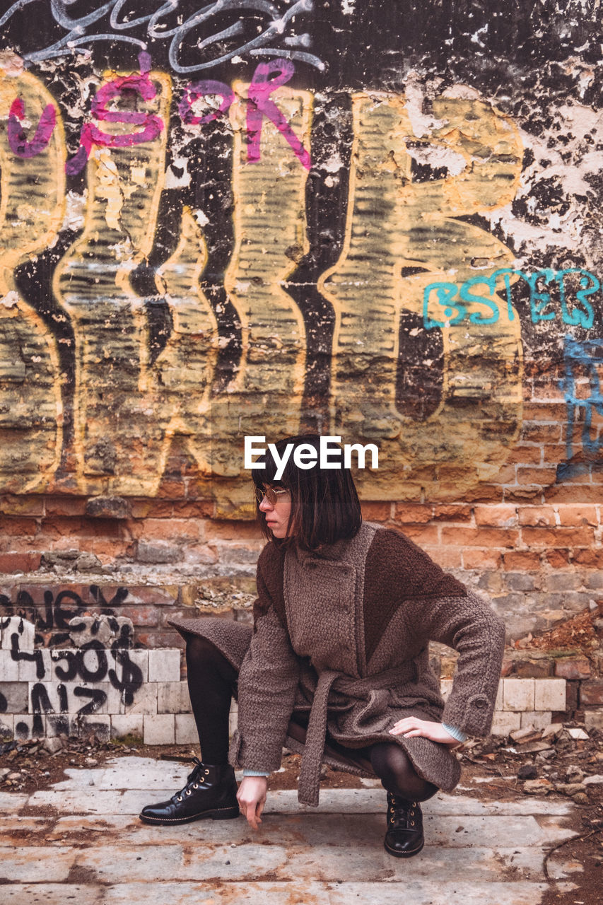 WOMAN WITH GRAFFITI ON WALL