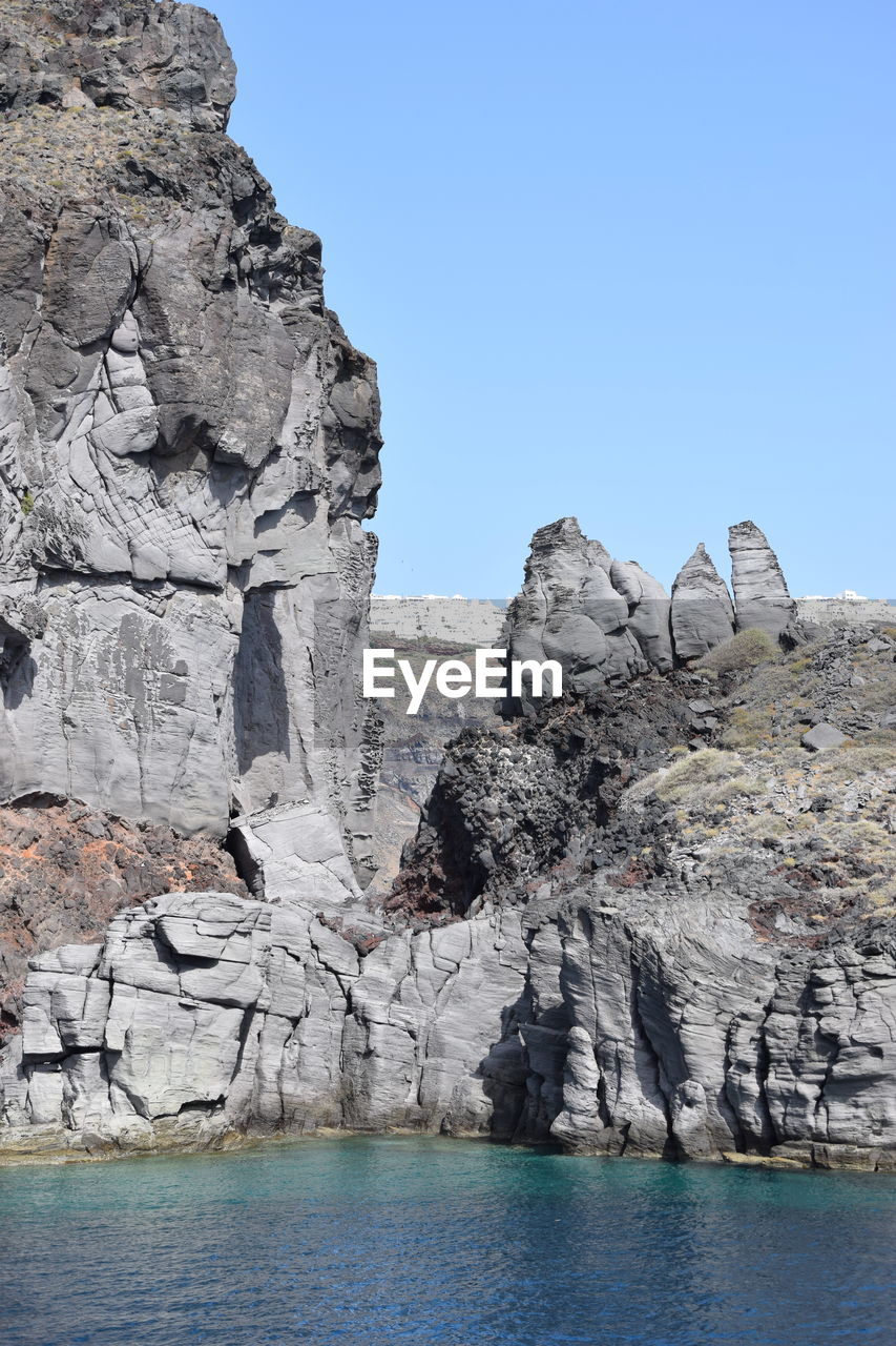 ROCK FORMATIONS BY SEA AGAINST CLEAR SKY