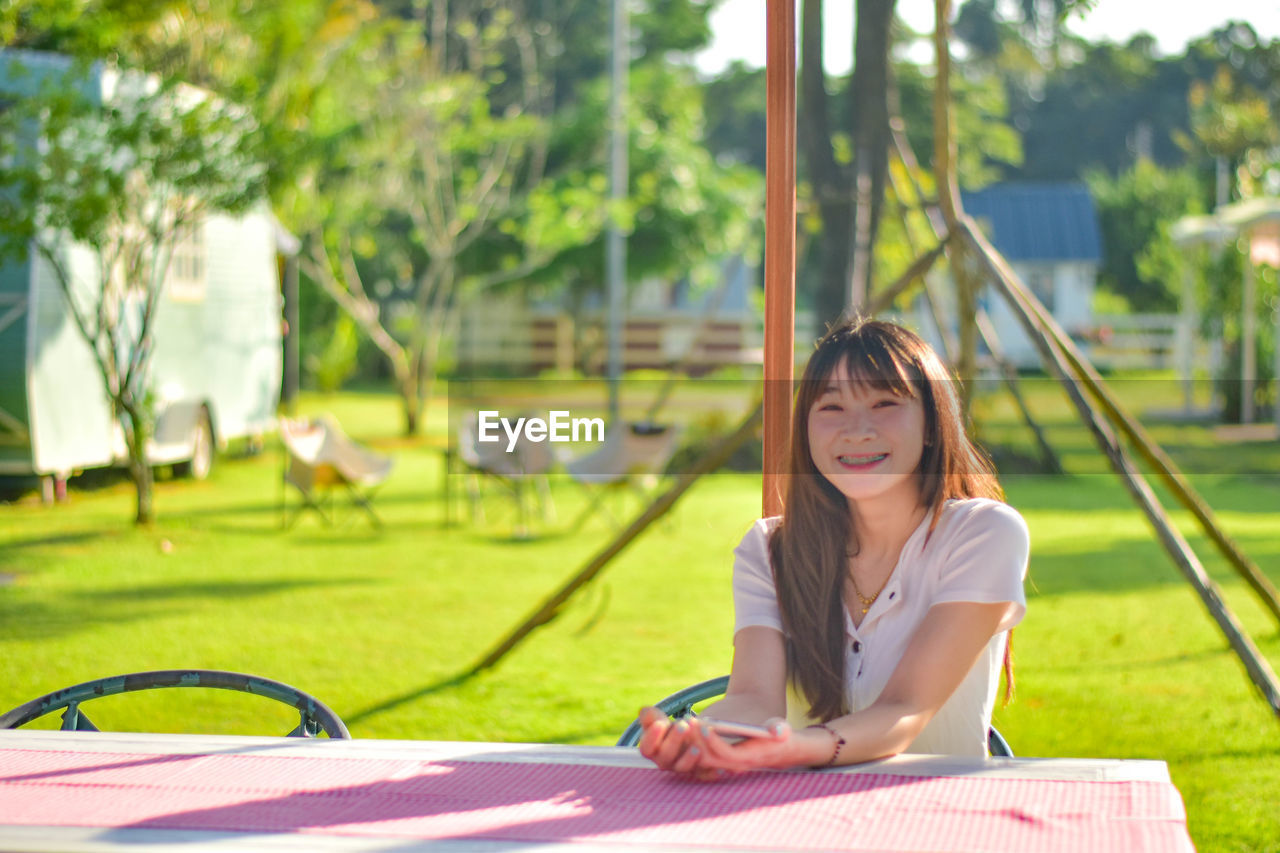 young woman using mobile phone while sitting on swing