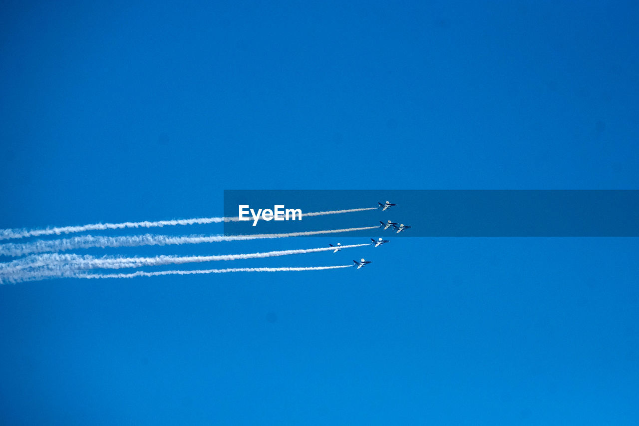 LOW ANGLE VIEW OF AIRSHOW AGAINST VAPOR TRAIL IN SKY