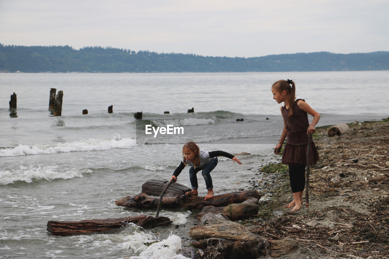 Two little girls playing at beach barefoot 