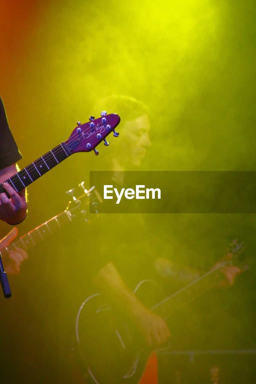 Side view of musician playing guitar seen through green smoke