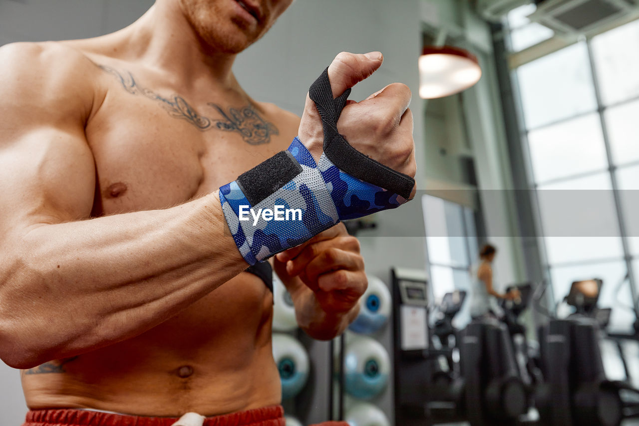 Muscular man wearing straps in gym