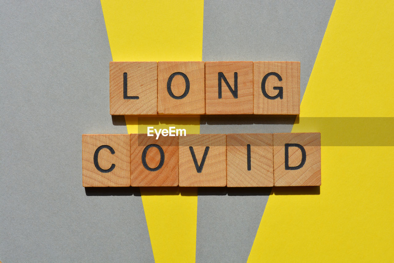 Long covid, words in wooden alphabet letters isolated on yellow and grey background