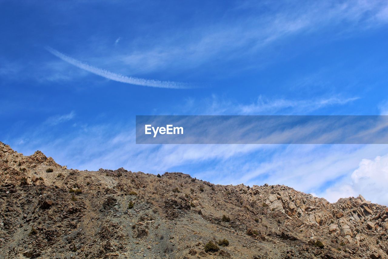 LOW ANGLE VIEW OF MOUNTAINS AGAINST BLUE SKY