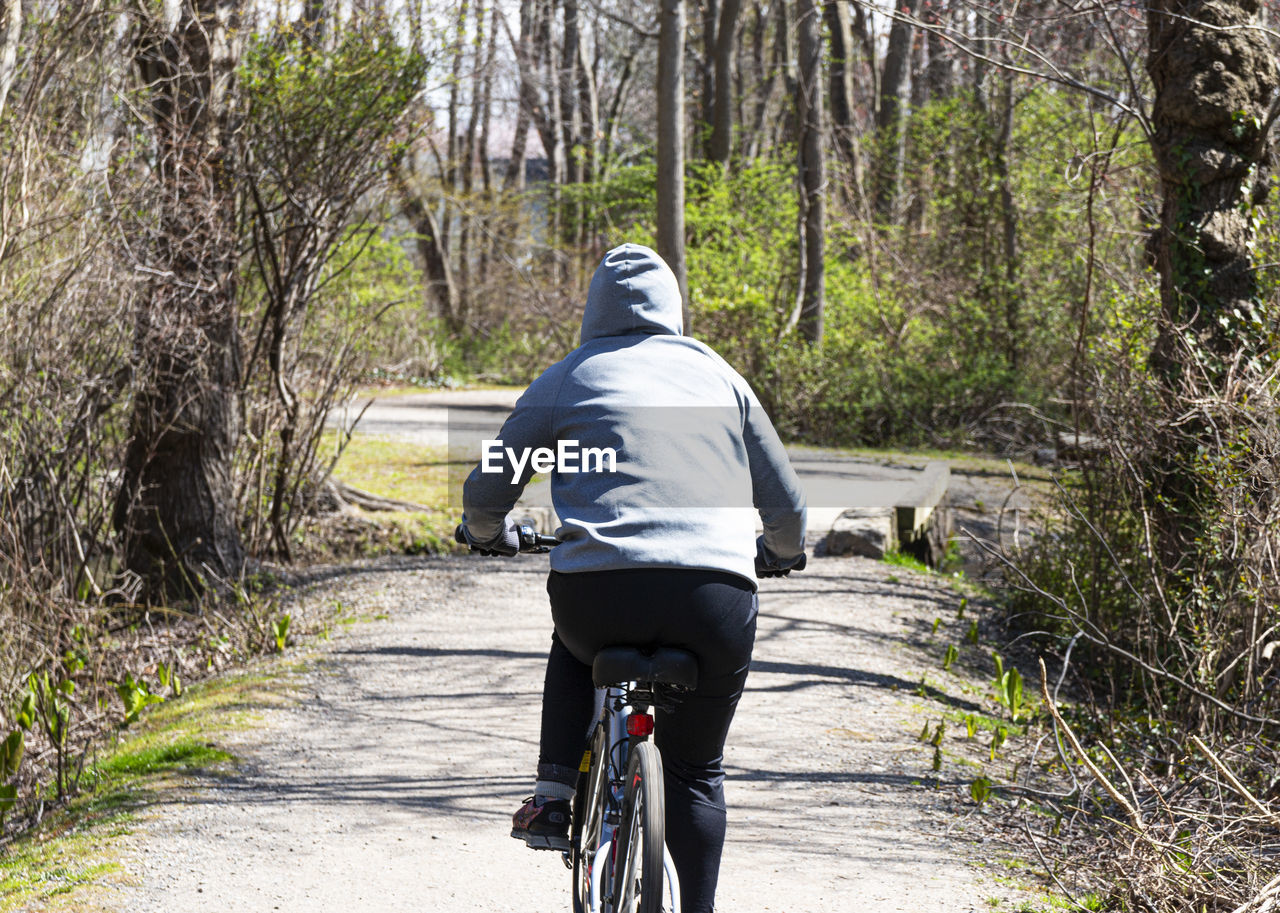 REAR VIEW OF PERSON RIDING BICYCLE ON ROAD