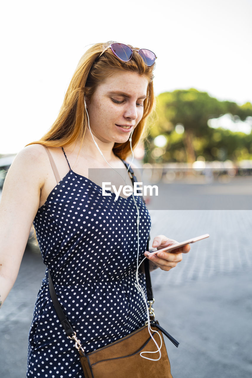 Glad female in earphones using smartphone
