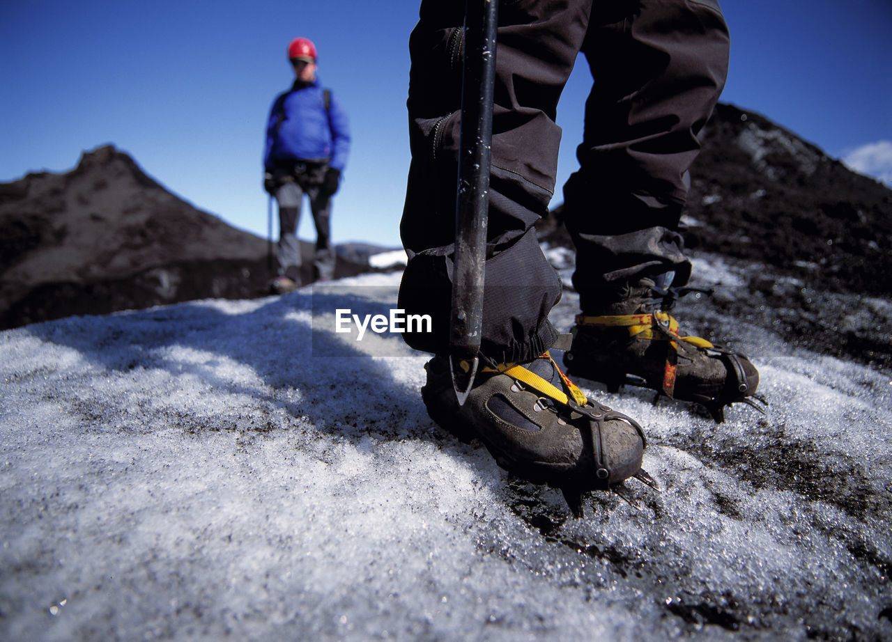 Close up of man wearing crampons on glacier