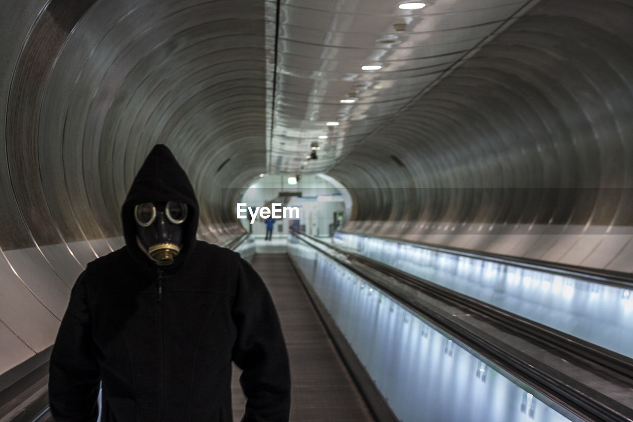 FULL LENGTH PORTRAIT OF MAN STANDING IN ILLUMINATED UNDERGROUND