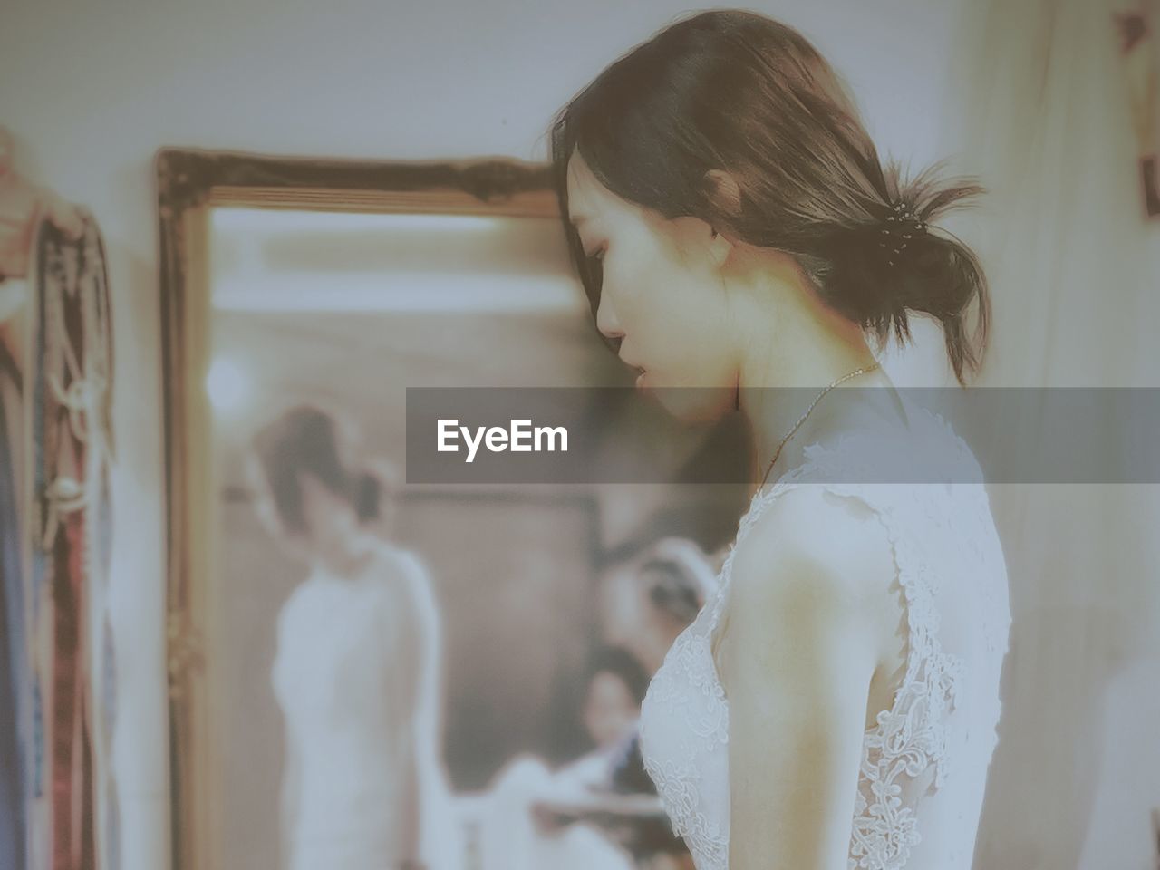 Side view of bride standing by mirror at home