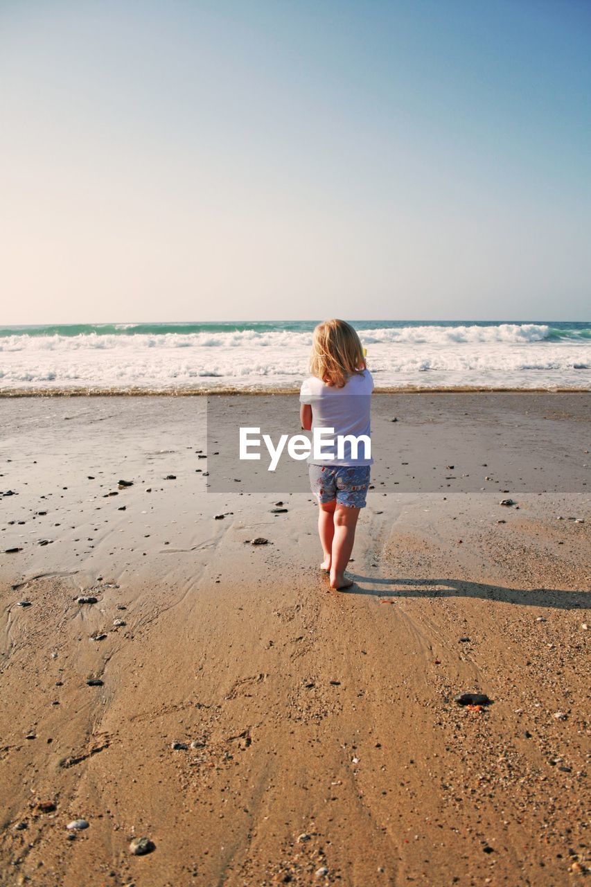 Rear view of girl standing on beach