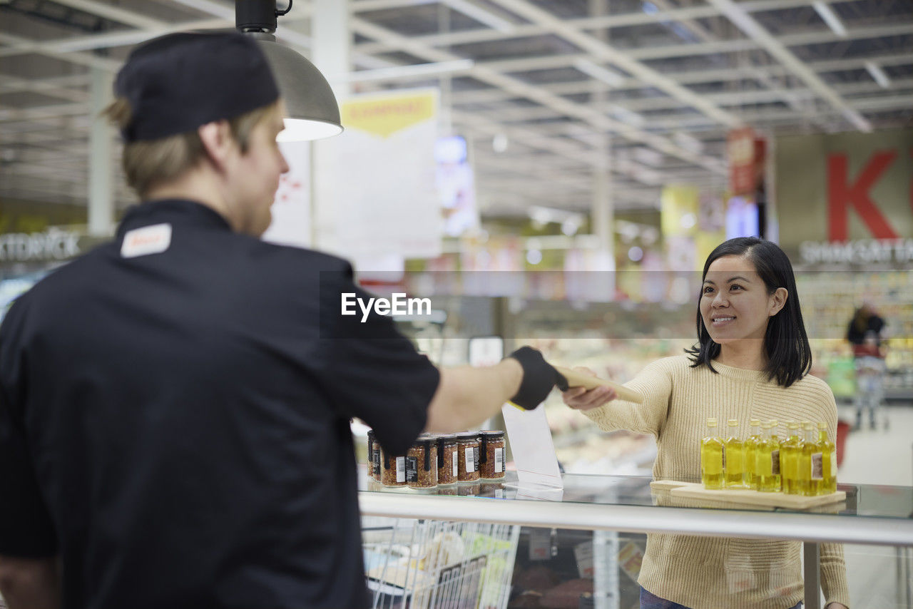 Female customer in supermarket buying products at deli counter