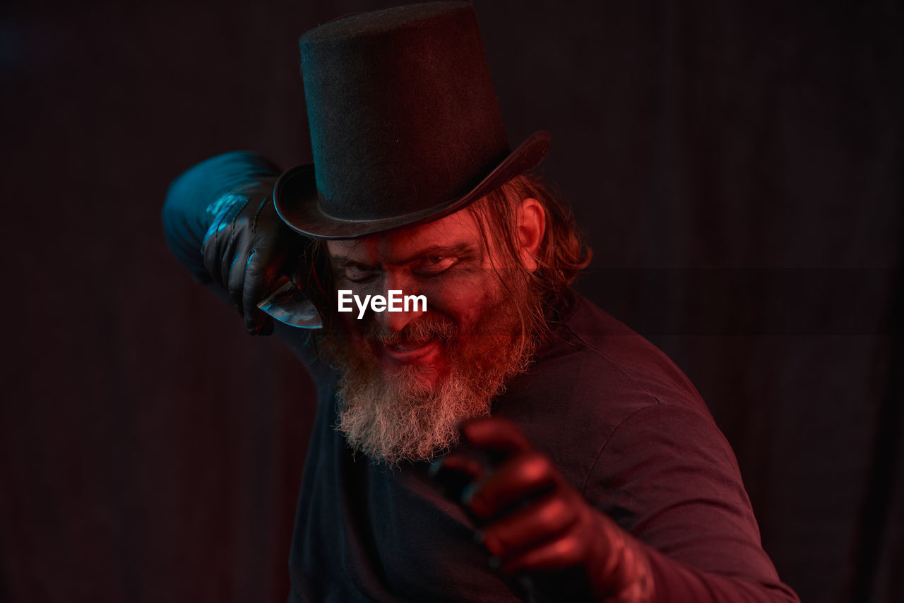 facial hair, adult, one person, beard, men, hat, red, clothing, performing arts, portrait, indoors, human face, fedora, dark, person, emotion, performance art, studio shot, stage, performance, entertainment, copy space, darkness, arts culture and entertainment, night, black background