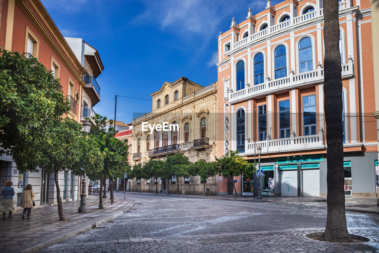 STREET BY BUILDINGS AGAINST SKY